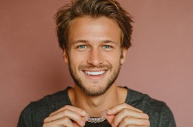 Smiling man holding an Invisalign aligner