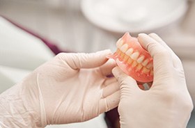 Gloved hands holding complete set of dentures