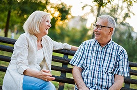 Senior couple sitting on park bench, chatting
