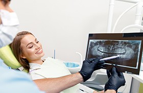 Dentist and patient looking at X-ray that includes wisdom teeth