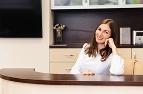 Friendly dental team member sitting behind desk