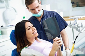 Patient looking at her teeth in mirror after dental cleaning