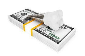Model implant and money representing the cost of dental implants in Branford