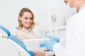 Happy dental patient looking at information on tablet