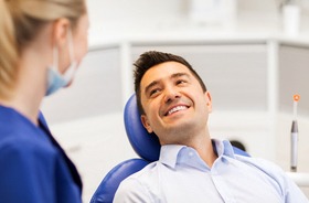 A middle-aged man lying in a dentist’s chair smiling at the dentist