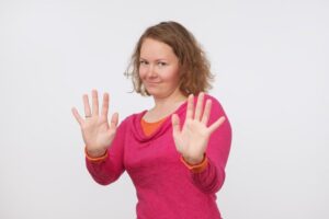 Woman in pink sweater making “no thanks” gesture 